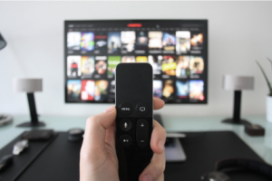 a person holding a remote control in front of a TV