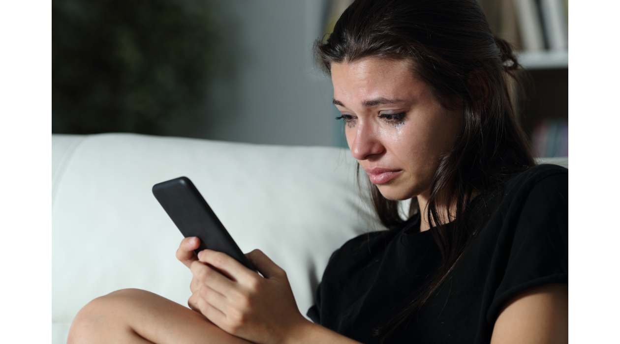 a girl crying looking at her phone
